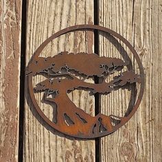 a metal tree on top of a wooden wall next to a fence with trees in the center