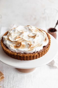 there is a pie with whipped cream on it sitting on a white plate next to some crackers