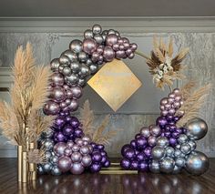 a purple and silver balloon arch with flowers