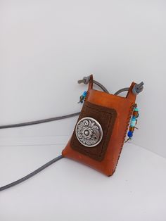 a brown leather pouch with a silver medallion on the front and blue beads around it