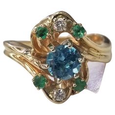 Specifications: main stone: 1 round Blue Topaz 1.00cts. other stones: 4 round emeralds .20pts. DIAMONDS: 2 round diamonds .05pts. color:GH clarity:VS2-SI1 brand:- metal:14K GOLD type: ring weight:7.6GrS size:8 US Blue Emerald Ring For May Birthstone, Round Shape, Blue Emerald Ring For May Birthstone, Blue Multi-stone Emerald Ring For Anniversary, Green Multi-stone Round Topaz Ring, Green Multi-stone Topaz Ring, Round Emerald Multi-stone Cluster Ring, Emerald Multi-stone Cluster Ring, Emerald Cluster Ring With Multi-stone, Topaz Yellow