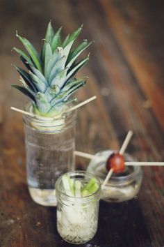 a pineapple sitting on top of a wooden table next to a jar filled with liquid