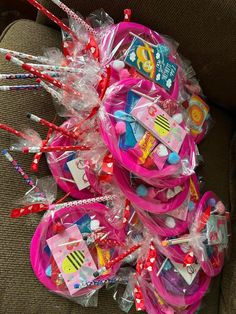 a pile of pink plastic bags filled with lots of candy and candies on top of a couch