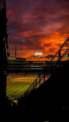 the sun sets over a baseball stadium as people watch from the bleachers at night