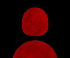 two red traffic lights with the moon in the dark sky behind them, all lit up