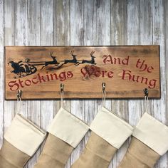 three stockings hanging from hooks in front of a sign that says and the stockings were hung