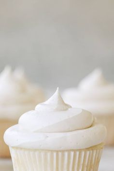 cupcakes with white frosting sitting on a table