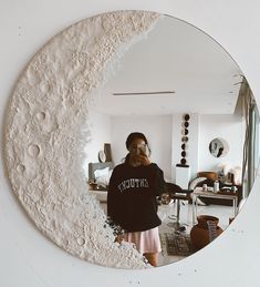 a woman standing in front of a mirror with the moon on it's side