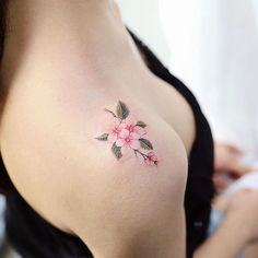 a woman's breast with pink flowers on her left side and green leaves in the middle