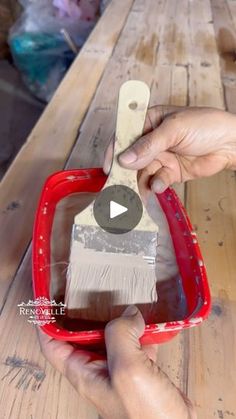 a person is holding a paintbrush in their hand and painting the inside of a red bowl