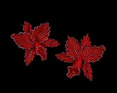 two red beaded flowers on black background