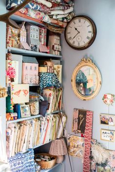 a room filled with lots of assorted items and a clock above the bookshelf