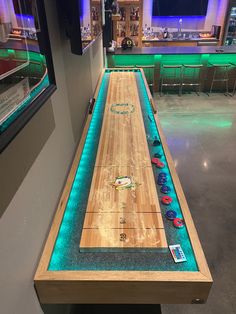 an indoor bowling alley is lit up with blue lights and remotes on the table