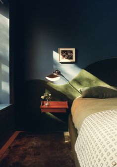 a bedroom with a bed, desk and lamp in it's corner next to a window