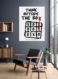 a chair and table in a room with a poster on the wall above it that says think outside the box