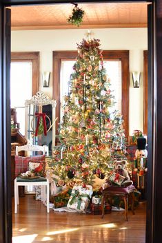 a decorated christmas tree in the middle of a living room with presents on the floor