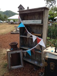 an old wooden cabinet with flags hanging from it's sides and other items on the ground