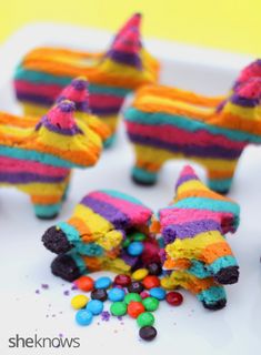 there are some colorful cakes made to look like animals with candy in their mouth and on the ground