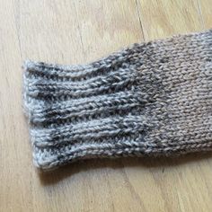 a close up of a knitted mitten on a wooden floor