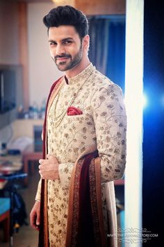 the man is wearing a white and red outfit with gold details on his chest, standing in front of a mirror