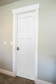 an empty room with a white door and carpet