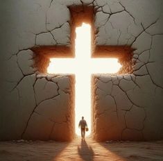 a man standing in front of a cross on a cracked wall with the light coming through it