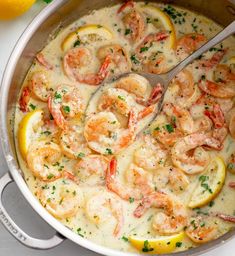 a pot filled with shrimp and lemons on top of a table