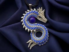 a blue and silver dragon pendant on a black leather cord with a purple bead necklace