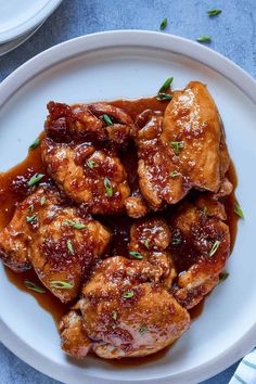 a white plate topped with chicken covered in sauce and garnished with parsley