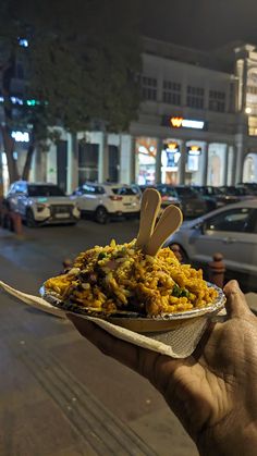 a person holding up a paper plate with food on it in front of a building