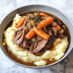 a bowl filled with mashed potatoes and carrots on top of a marble table