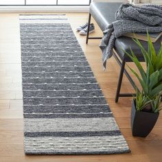 a large rug is sitting on the floor next to a chair and potted plant