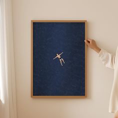 a woman is pointing at a painting on the wall with her hand in front of it