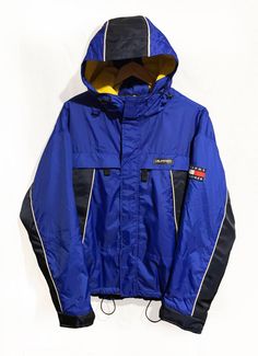 "Vintage 90's Tommy Hilfiger Athletic Gear Fleece Lined Winter Jacket Flag Logo Spell Out Color Block Navy /Blue/Yellow Size M Condition: Very Good Yellow /Blue/White Color Block Tommy Hilfiger Classic Flag Logo Patch Embroidered on Left Arm Heavy Duty Zipper Close Pockets on Front of Jacket Fleece Lining Inside of Jacket - Adjustable Strap Wrist Cuffs Measurements Pit-to-Pit: 24\"/64cm Top-to-Bottom: 28\"/71cm pit to cuff: 21\"/54cm Please keep in mind that colours from the pictures may vary be Retro Yellow Windbreaker For Winter, Vintage Windbreaker For Fall Winter Sports, Vintage Yellow Windbreaker For Winter, Vintage Long Sleeve Windbreaker For Cold Weather, 90s Style Winter Sports Outerwear, 90s Style Outerwear For Winter Sports, Yellow Long Sleeve Hooded Jacket For Winter, Yellow Long Sleeve Hooded Winter Jacket, Vintage Winter Sports Outerwear With Pockets