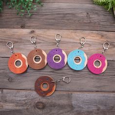 five different colored doughnuts are on a wooden table next to a metal keychain