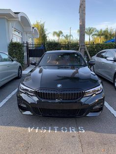 two cars parked next to each other in a parking lot with palm trees behind them