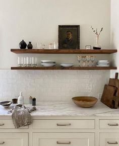 a kitchen with white cabinets and shelves filled with plates, bowls and utensils