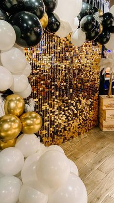 balloons and streamers are hanging from the ceiling in front of a gold sequin backdrop