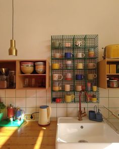 a kitchen area with a sink, counter and shelves on the wall