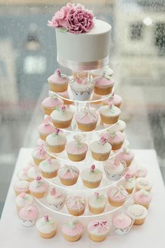 cupcakes are arranged in the shape of a wedding cake with a flower on top