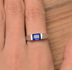 a woman's hand with a ring on it and a blue stone in the middle