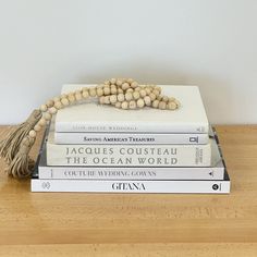 three books stacked on top of each other next to a tasseled bead