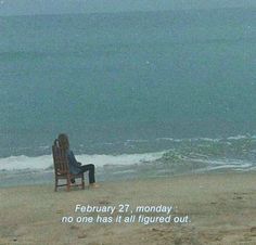 a person sitting in a chair on top of a beach next to the ocean,