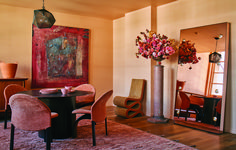 a dining room table with chairs and a vase filled with flowers on top of it