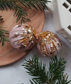 two ornaments sitting on top of a wooden plate