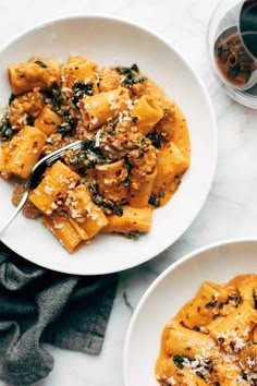 two white plates filled with pasta and sauce