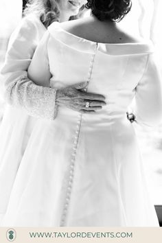 a woman in a white dress standing next to a window with her hands on her hips