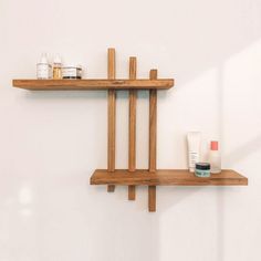 two wooden shelves with various items on them against a white wall in a bathroom area