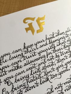 a handwritten letter is on top of a piece of paper with gold foiling