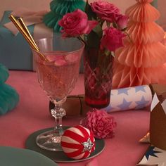 a table topped with pink roses next to a vase filled with water and candy canes